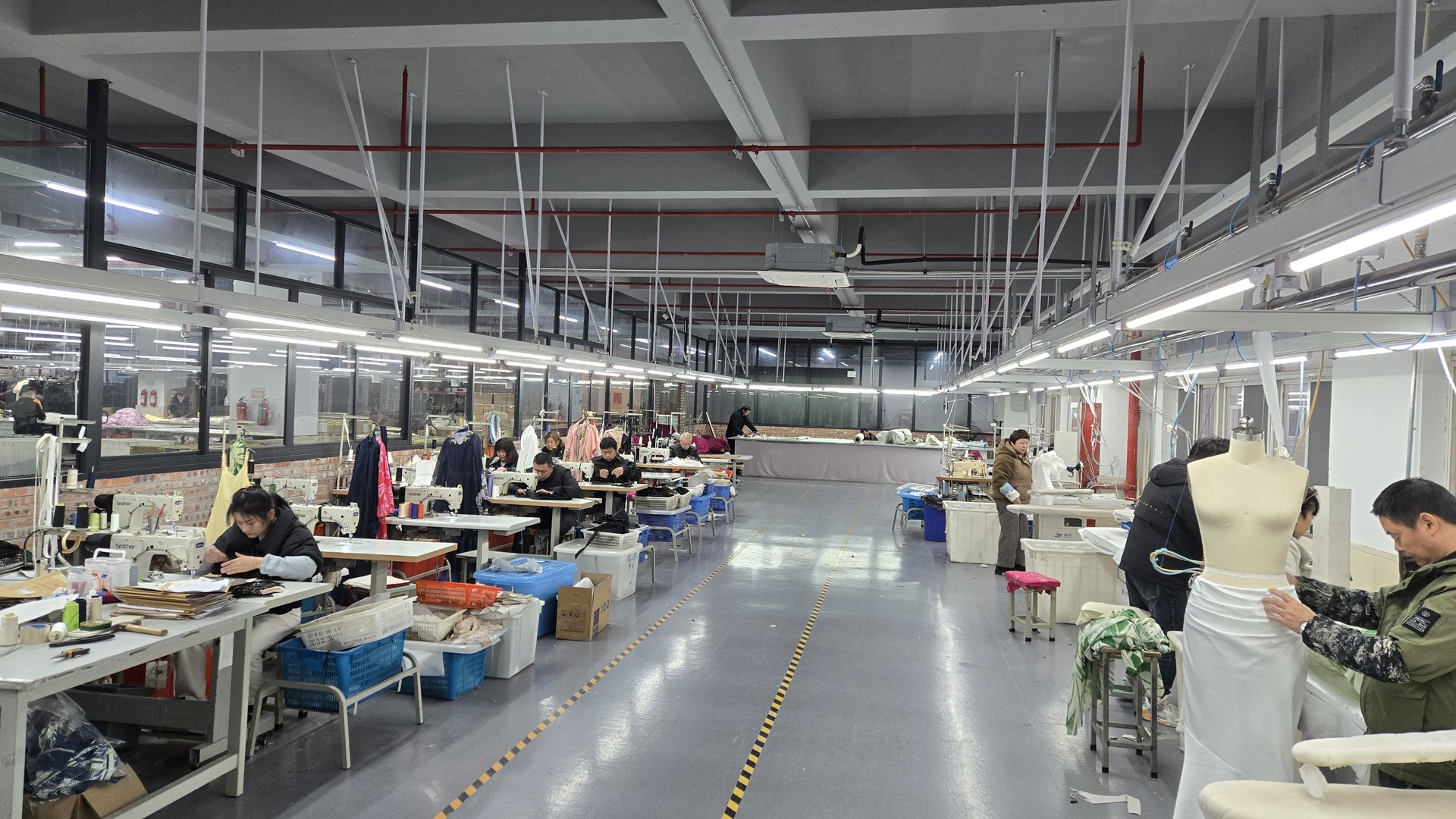 Deepwove Hangzhou sample room — pattern bench with cutting tables and dress forms in natural workshop lighting