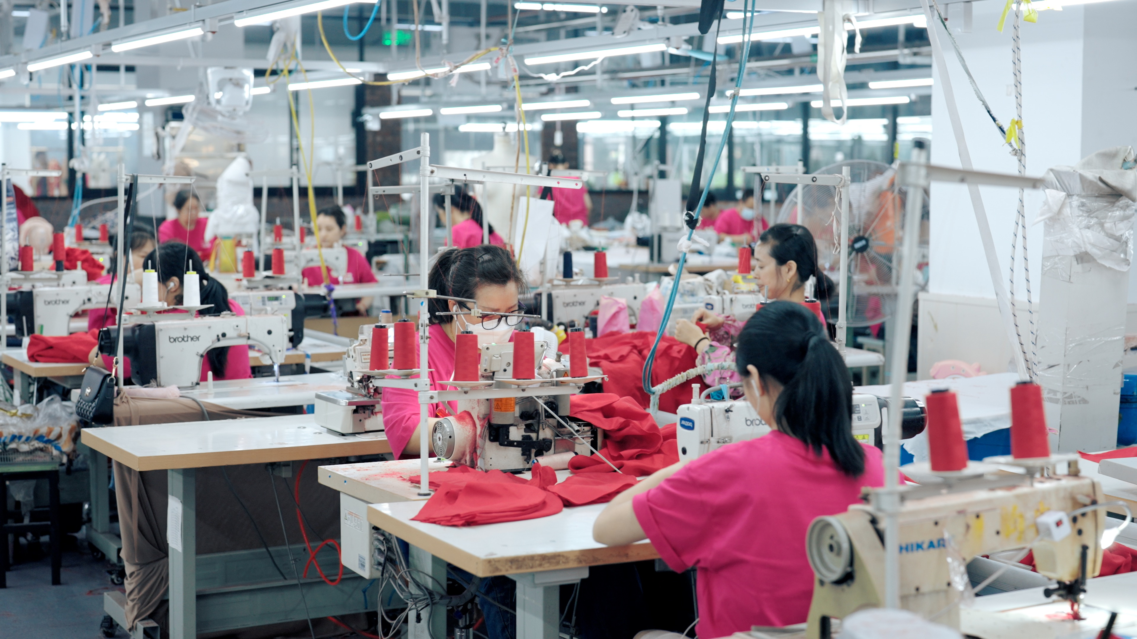 Production floor with multiple sewing stations — bulk garment manufacturing in progress